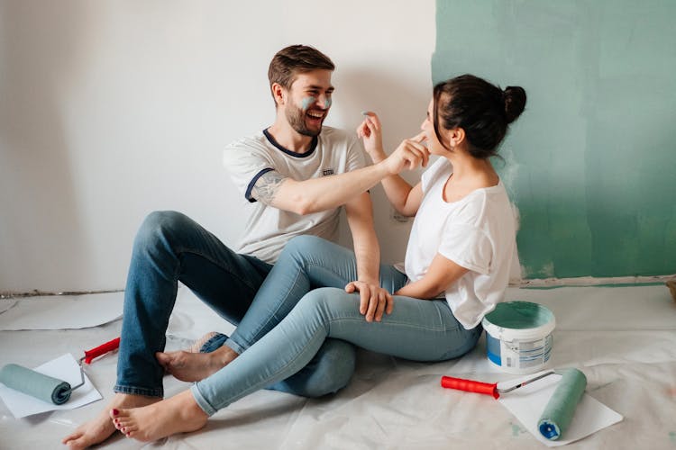 Happy Couple Sitting On The Floor With Paint On Their Faces