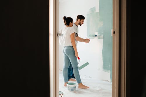 Man Painting Wall Beside a Woman