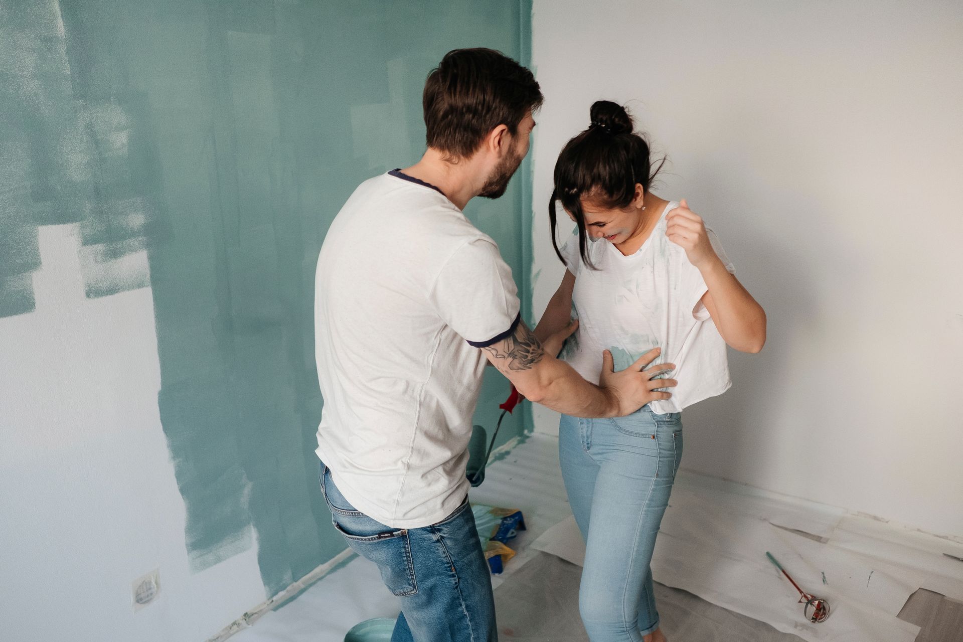 A Couple Laughing Together while Doing Painting