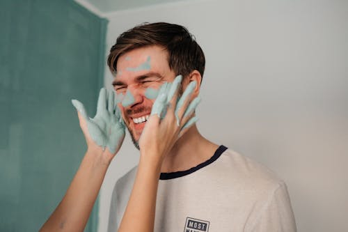 Hands with Paint Near a Man's Face