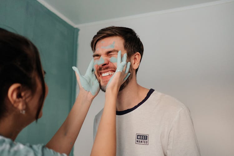 Woman With Paint On Her Hands Touching The Face Of A Man