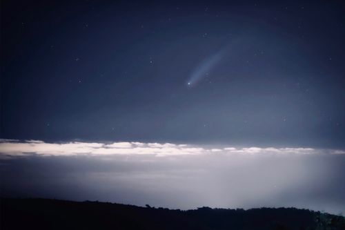 Free Astounding view of a luminous comet streaking across a starry night sky above a cloud layer. Stock Photo