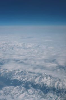 Breathtaking aerial view of snow-covered mountain peaks beneath a sea of clouds.