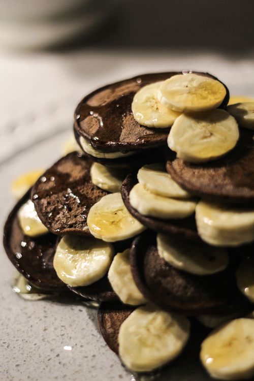 Free Stack of homemade chocolate pancakes topped with banana slices and honey for a sweet treat. Stock Photo