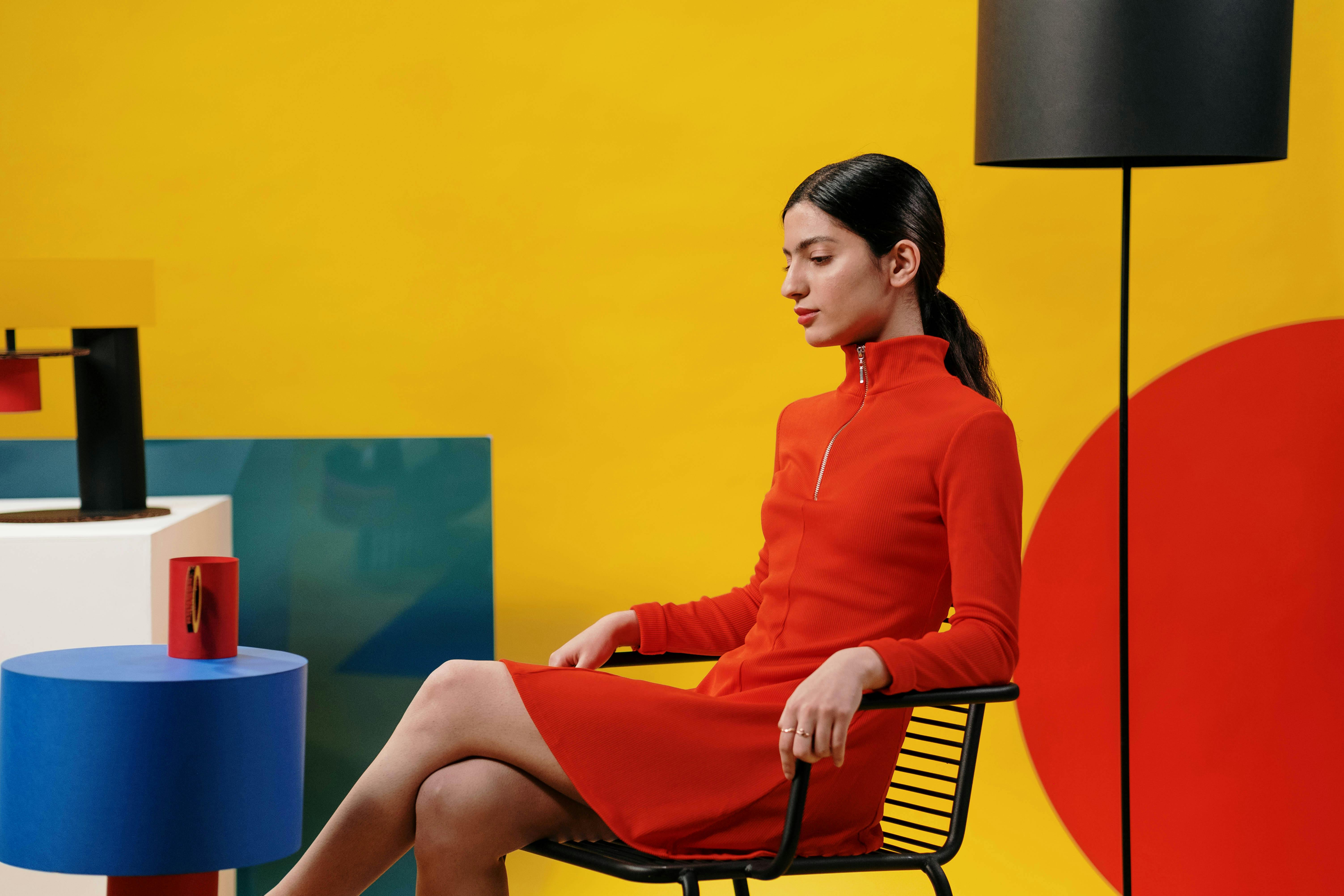 Creative studio portrait of a woman in a red dress against a vibrant yellow background.
