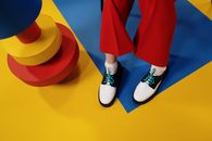 Person in Red Pants and White Sneakers Standing on Yellow Floor