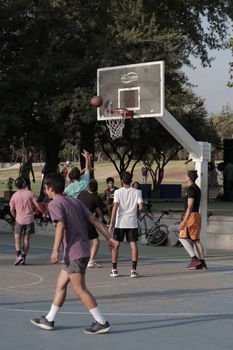 Exciting outdoor basketball game with teams engaging on the court, showcasing teamwork and athleticism.