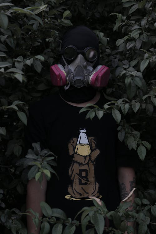 Free A Man Wearing a Gas Mask Standing Behind the Shrub Stock Photo