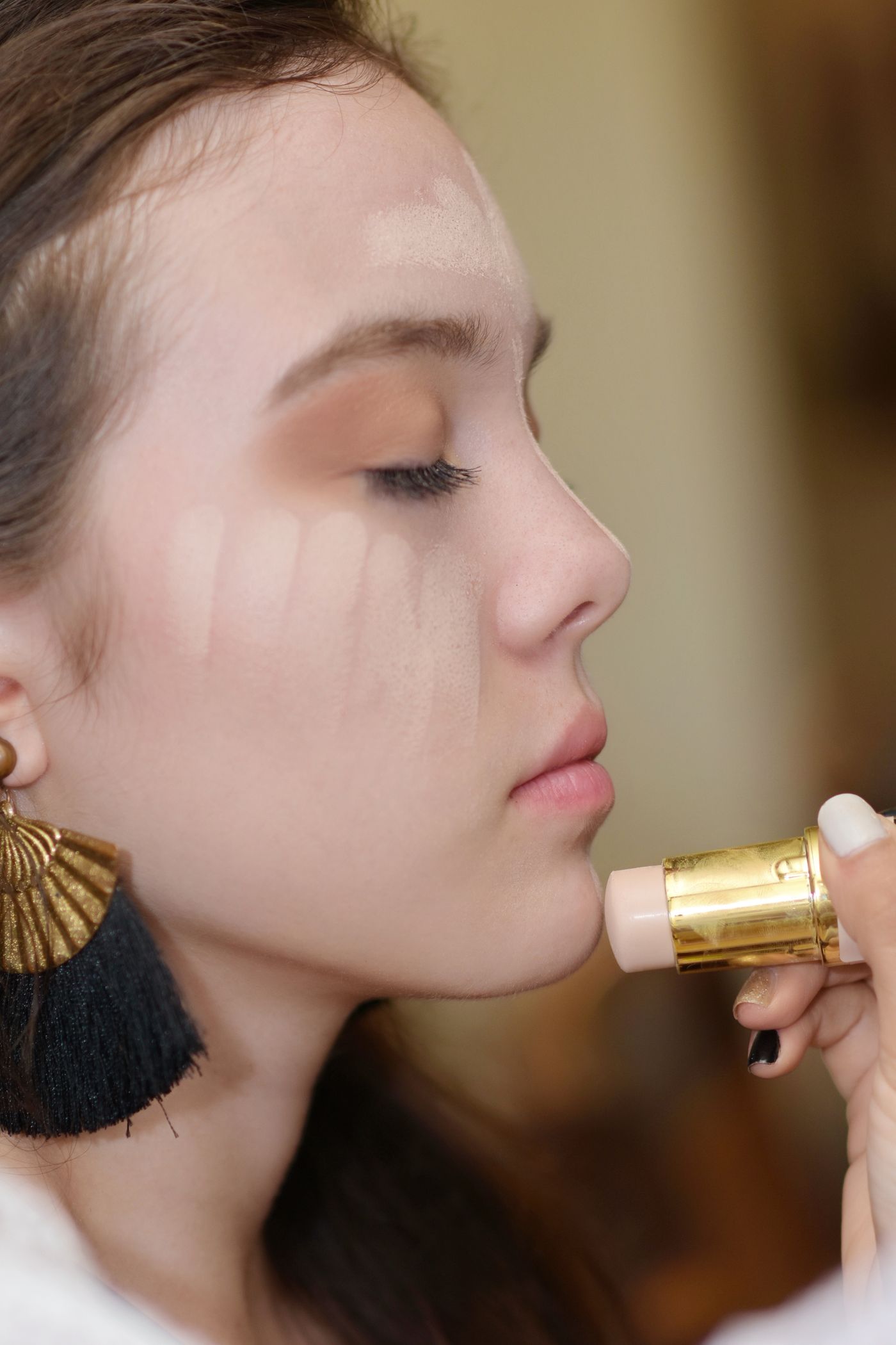 Woman applying concealer to cover acne without making it worse