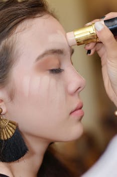 Close-up of a woman receiving professional makeup application with foundation stick.