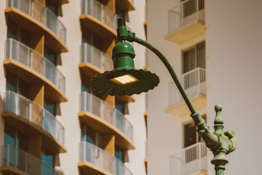Close-up of a vintage green street lamp against a backdrop of modern residential architecture.