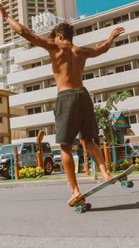 Topless young man skateboarding in an urban setting with arms outstretched, showcasing balance and freedom.