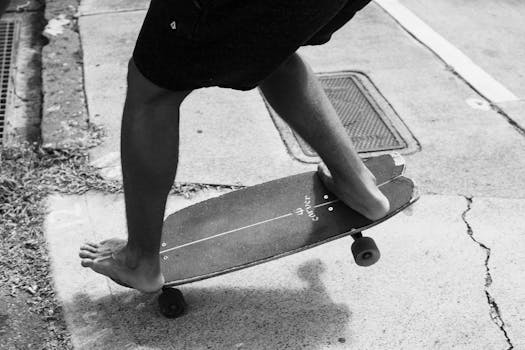 Black-and-white image of a person skateboarding barefoot, capturing a sense of freedom and adventure.