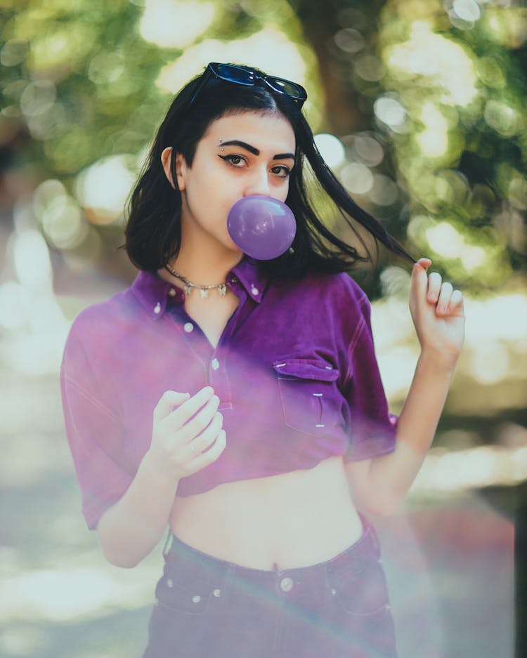 Young Woman Blowing Gum Bubble In Park