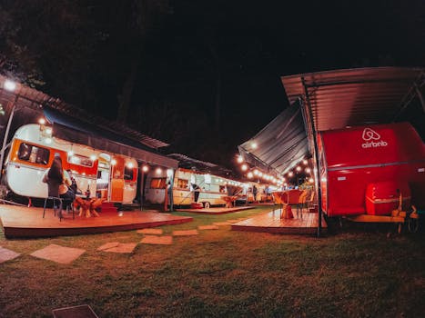 Cozy campsite with caravans and string lights, perfect for night camping enthusiasts.