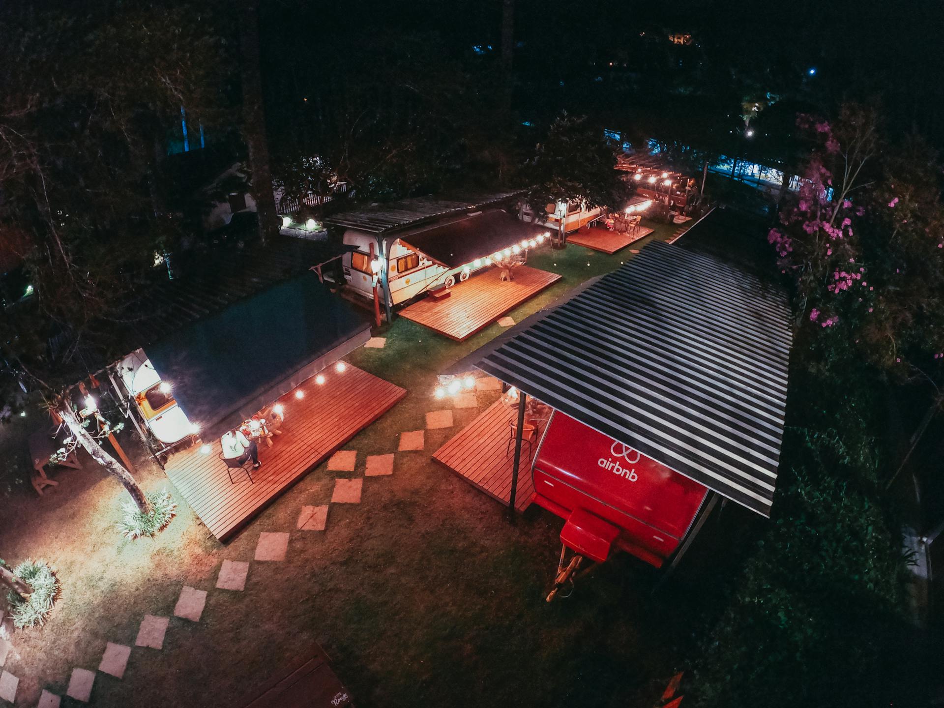 Aerial view of trailers for tourists at camping area decorated with sparkling garlands at night