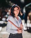 Smiling young ethnic female millennial standing on street in daylight