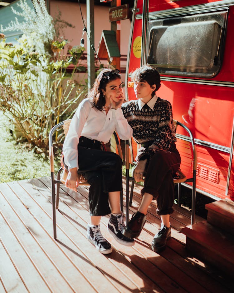 Trendy Young Ethnic Female Friends Relaxing On Chairs In Trailer Park