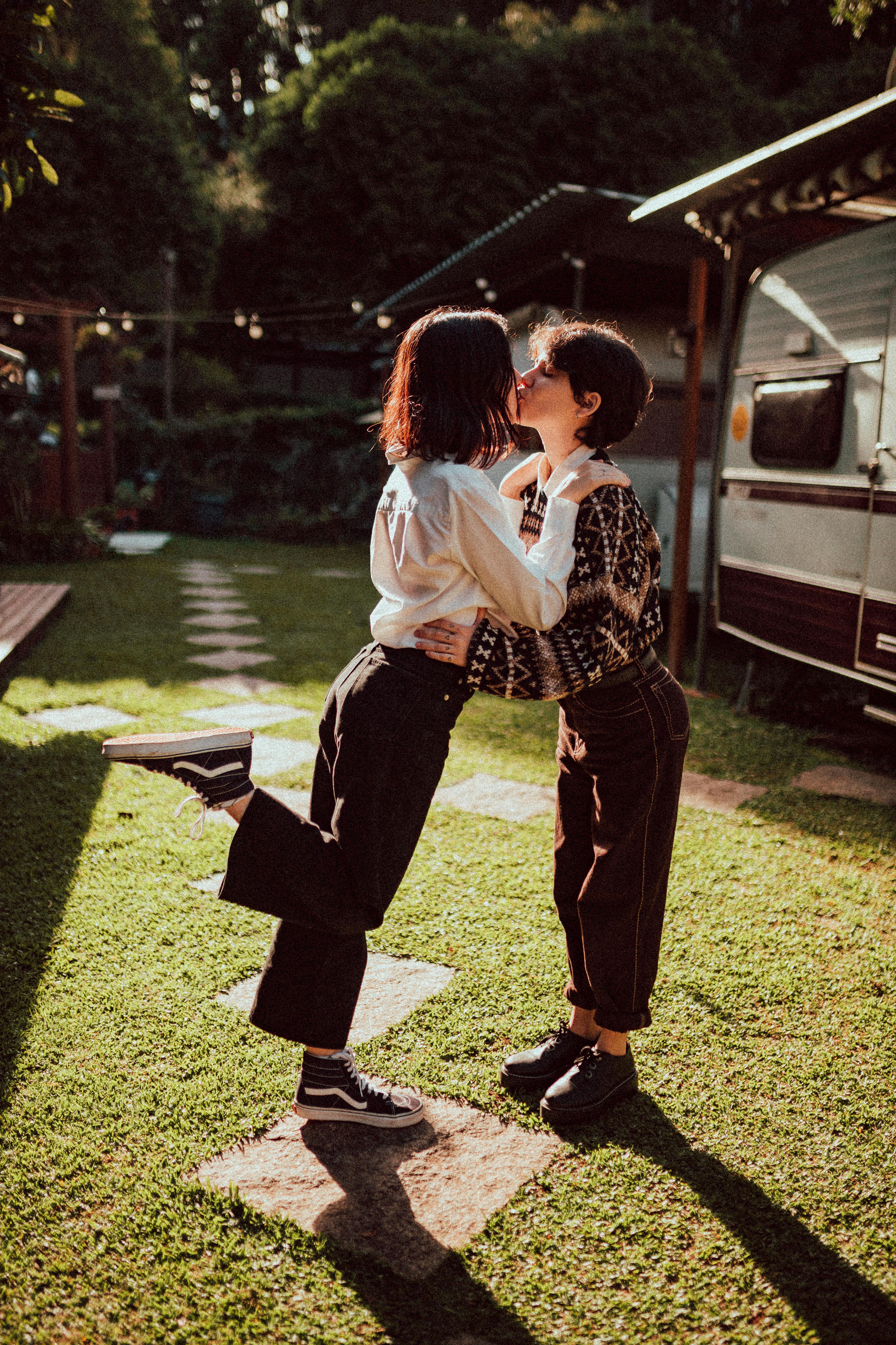 stylish homosexual female teenagers kissing in green park