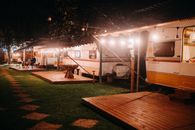 Unrecognizable girlfriends on platform against caravans in campsite