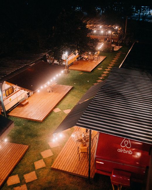 Fotomural Una vista aérea de un área de camping iluminada, con caravanas y plataformas de madera creando una atmósfera cálida.