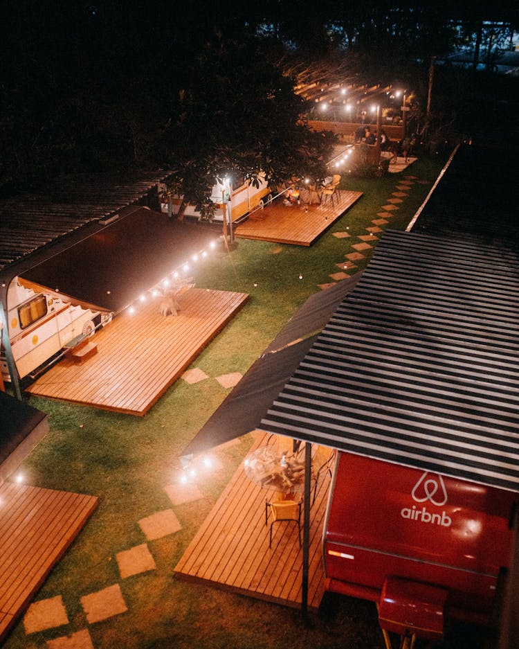 Campground With Caravans And Platforms Under Shiny Lamps At Dusk