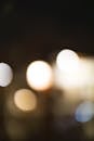 Defocused abstract bokeh backdrop with shiny white and beige lights under dark sky in evening