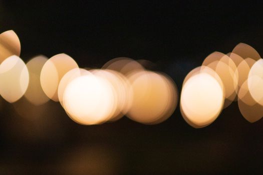 Abstract bokeh backdrop of bright oval and round shaped lights overlapping while spreading in twilight