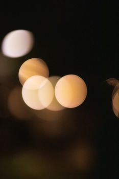 Abstract bokeh background of transparent round shaped beige lights diffusing in air at dusk