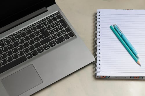 Photo of a Notebook Near Laptop
