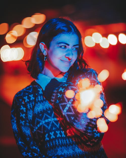Young woman in warm sweater with glowing sparkler