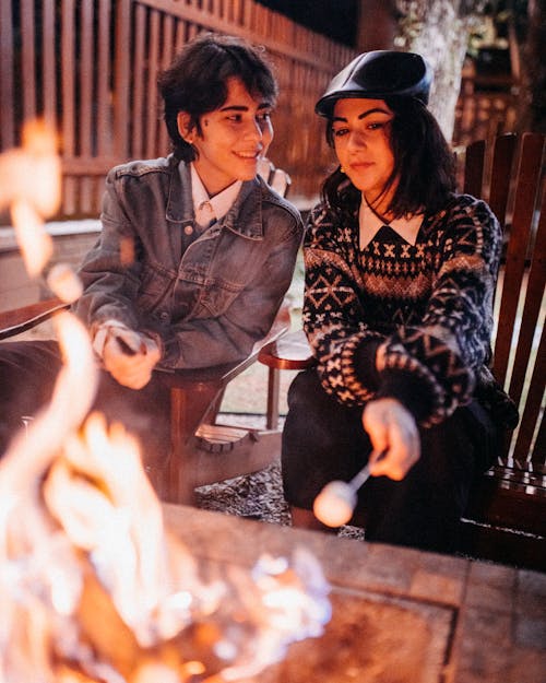 Friends sitting near fireplace with marshmallows