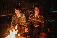 Friends frying marshmallow on bonfire