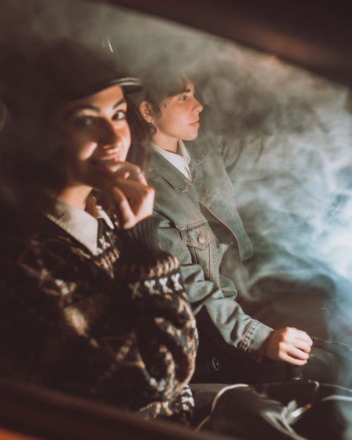 Free Young woman in ornamental sweater and cap biting nail against female friend driving transport during journey Stock Photo