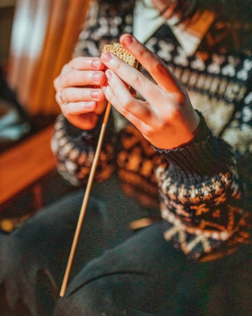 Crop woman preparing smore on stick in twilight