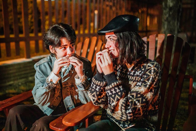 Girlfriends Enjoying Smores In Armchairs At Night