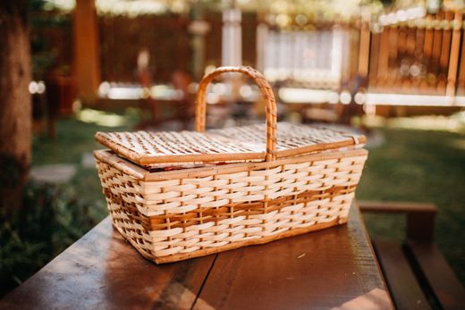 Two-tone wicker picnic hamper with hinged lid on outdoor wooden table