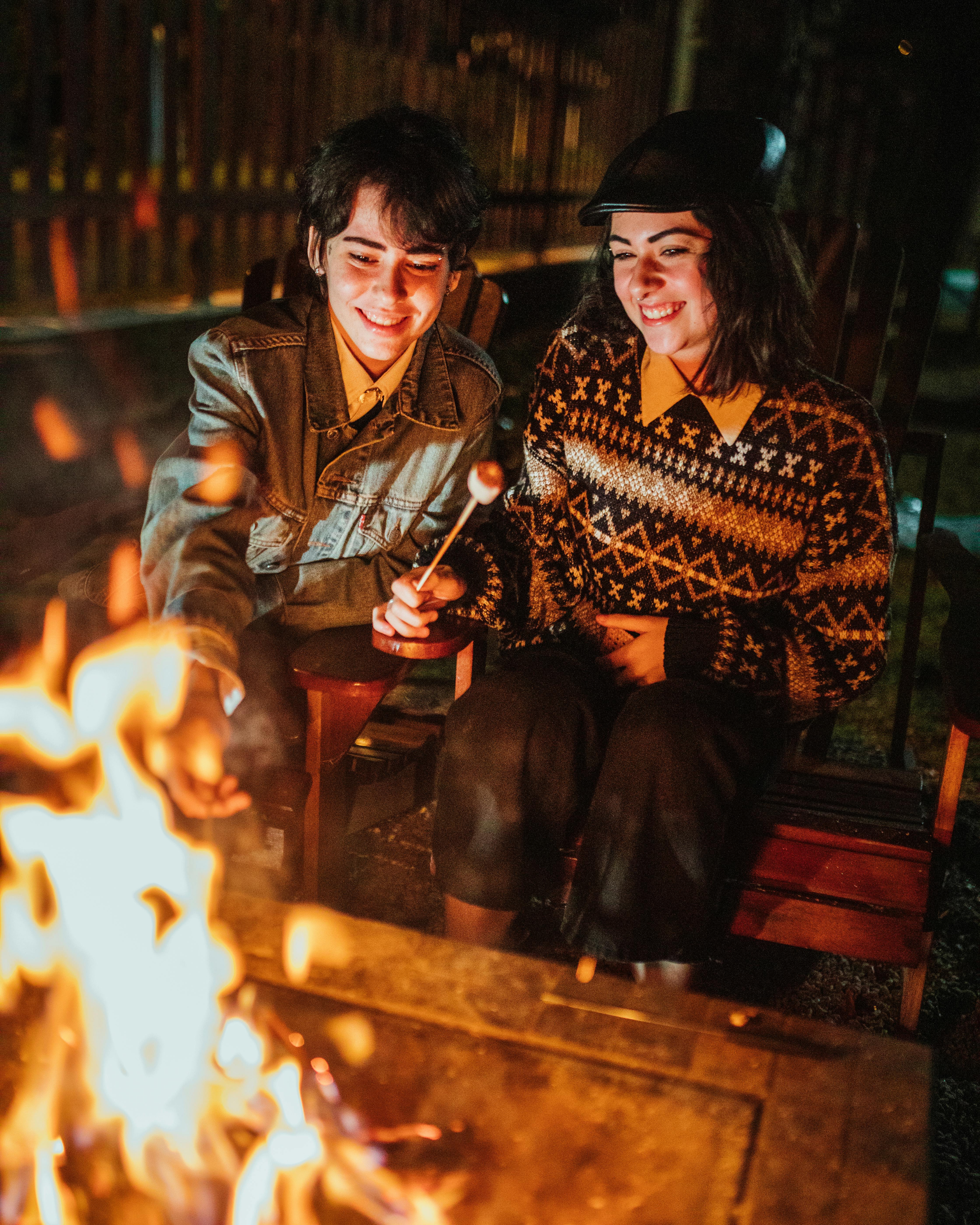 cheerful women eating marshmallow near bonfire