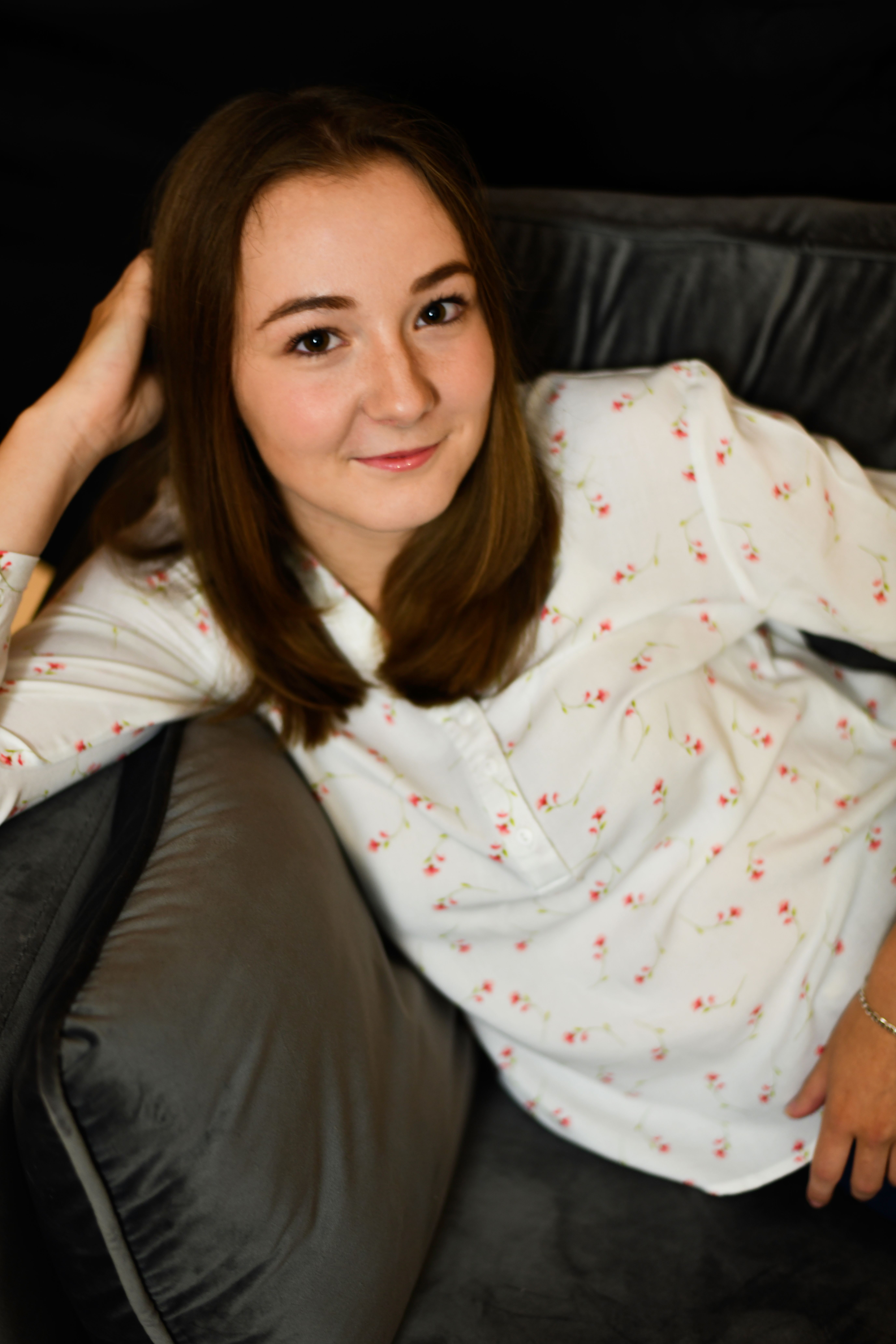 Woman relaxing on a couch, smiling casually in a cozy indoor setting.