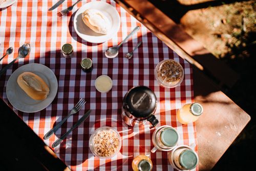 Free Top view composition of fresh buns on plates placed on tablecloth with thermos and juice during picnic on sunny summer day Stock Photo