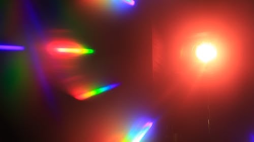 Free Lantern with bright glowing light placed in illuminated room with black walls and multicolored spectrum and refraction of shining light Stock Photo