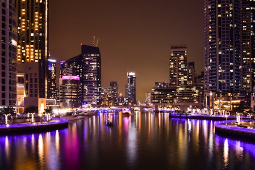 A breathtaking view of a city marina at night, with illuminated skyscrapers reflecting on the water.