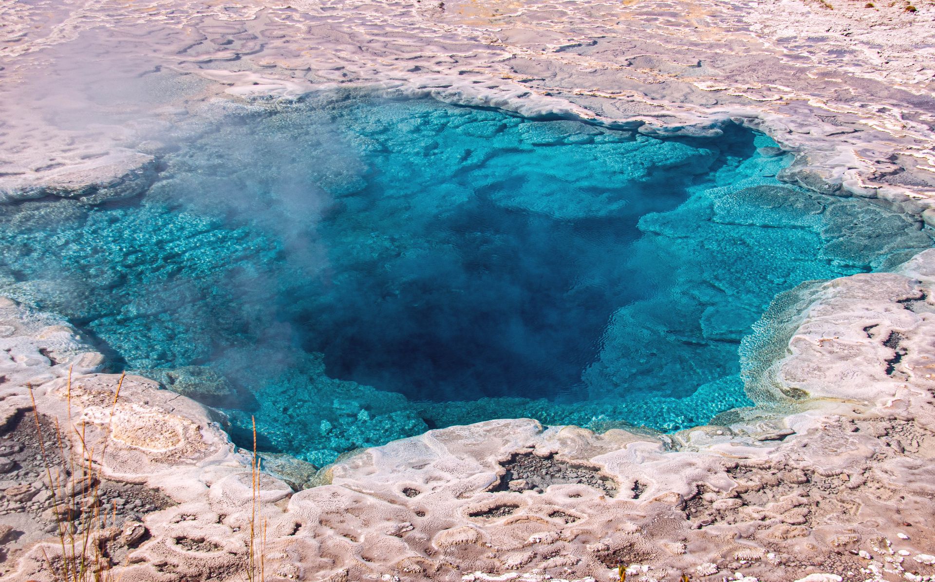 Vivid blue hot spring emitting steam at Yellowstone National Park's geothermal area.