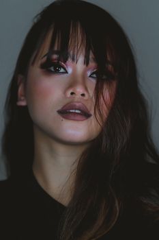 Close-up portrait of a woman with striking makeup and artistic lighting, showcasing expressive eyes.