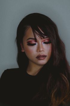 Captivating studio portrait of a woman with striking eye makeup and hairstyle.