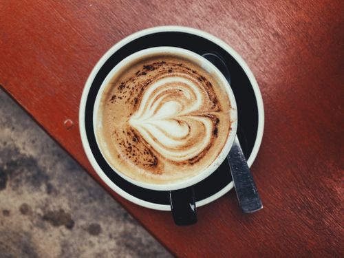 Free A close-up of heart-shaped latte art in a coffee cup, capturing the essence of a Thai cafe experience. Stock Photo