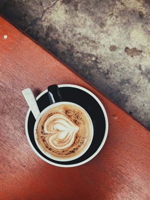 Free A beautifully crafted cappuccino with heart-shaped latte art in an elegant black cup and saucer. Stock Photo
