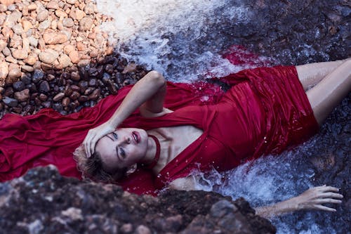 Woman in Red Dress Lying Down on Rocks