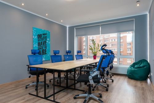 Free Blue armchairs at wooden table placed in modern conference room with decorative signboard with inscription and window in stylish office building Stock Photo