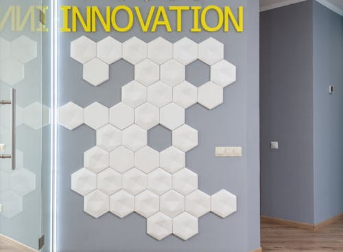 White geometric decorations on wall with yellow Innovation inscription in hallway of modern office building near glass door of room